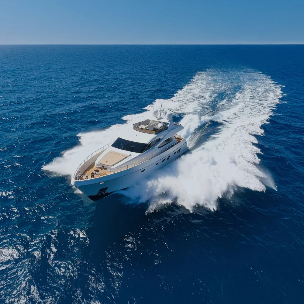 A motor yacht cruising at speed across open blue water
